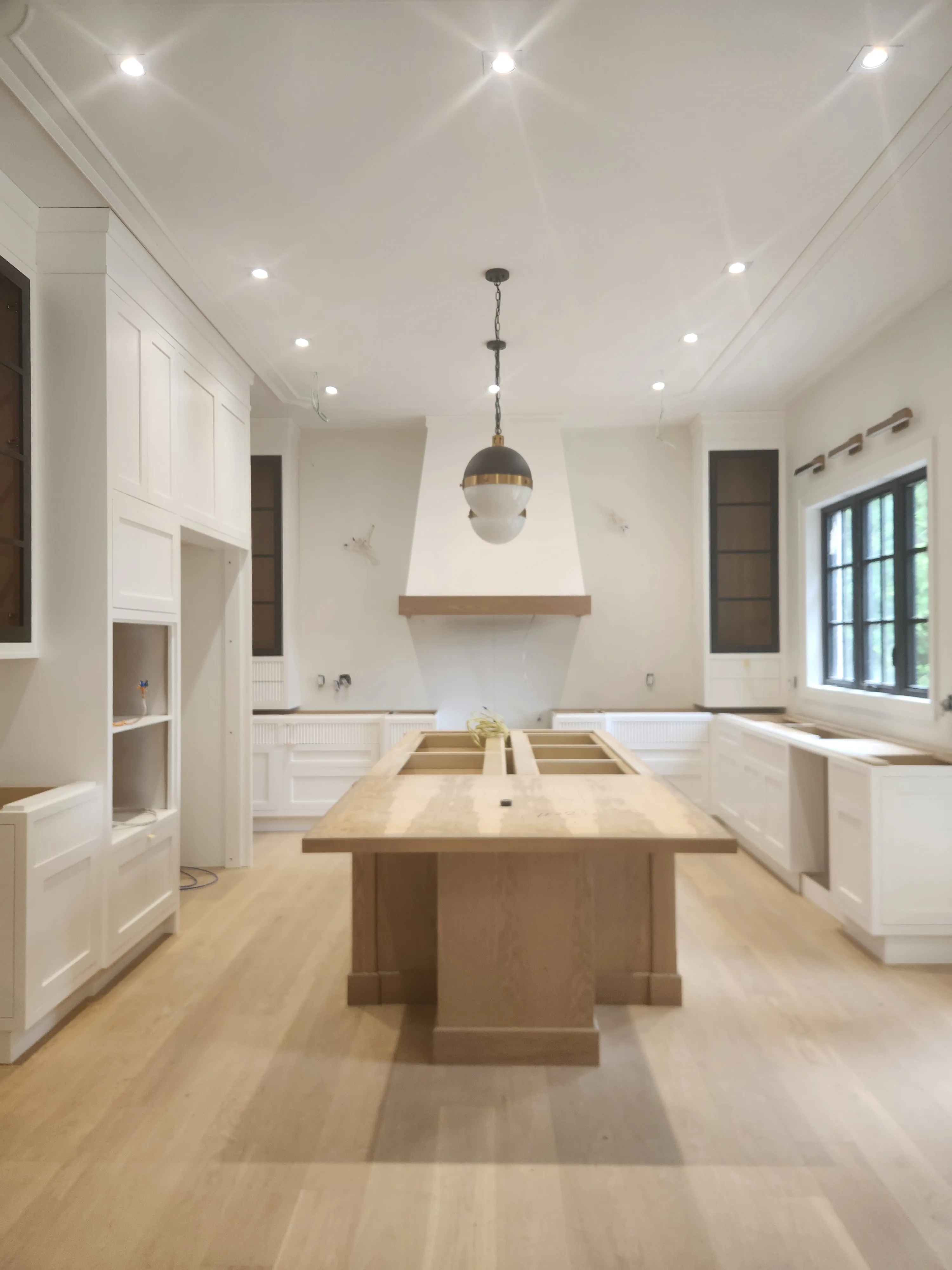 Kitchen repainting by Sigma Painting — white cabinetry and plaster range hood around a white oak island